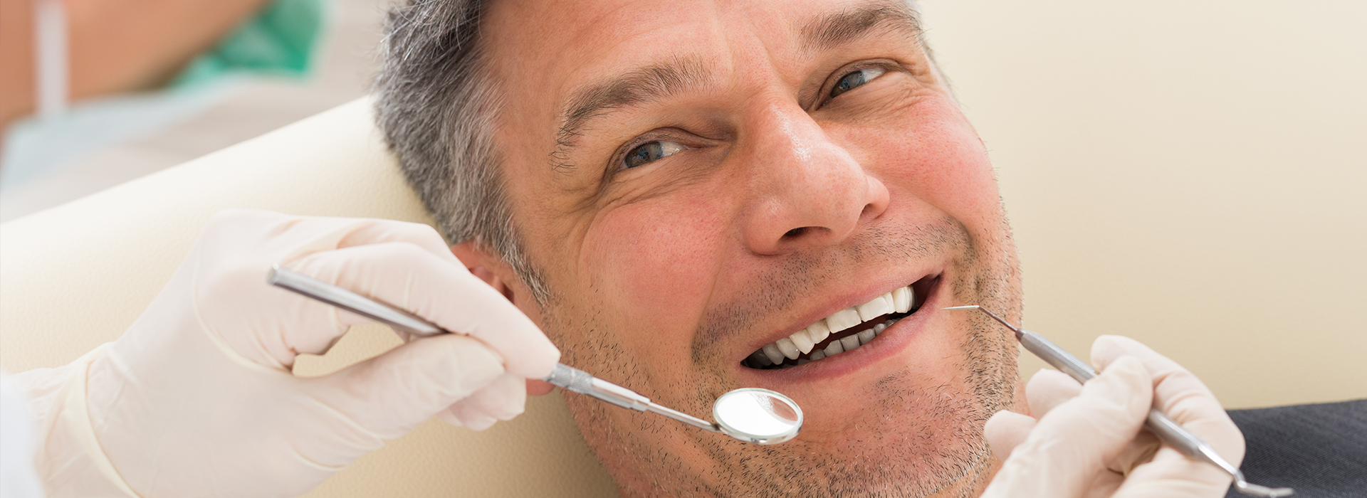 A man sitting in a dental chair with his mouth open while receiving dental treatment.