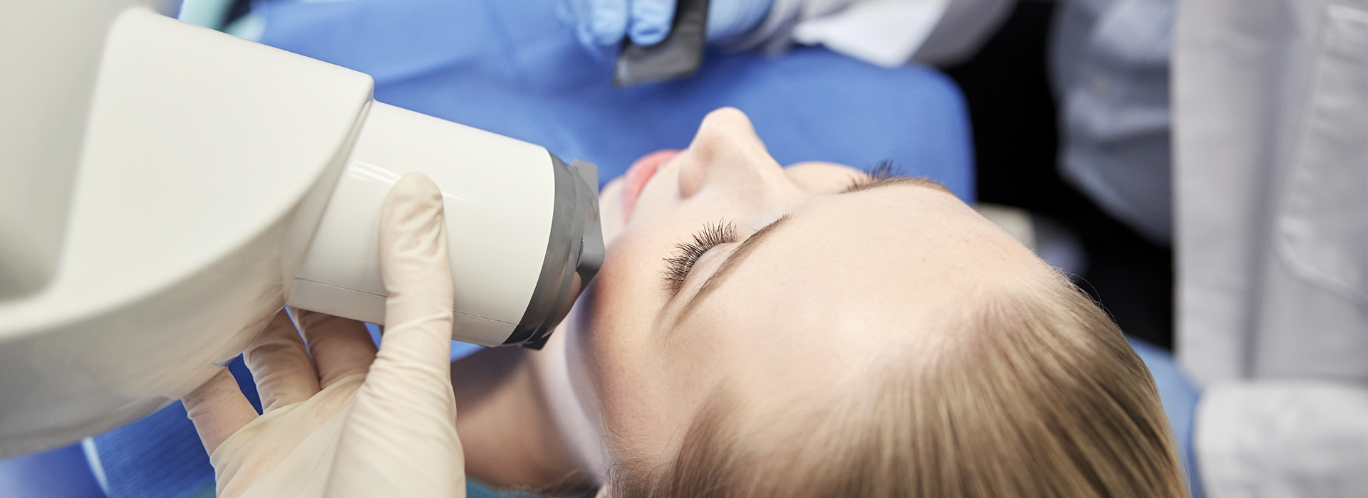 A woman receiving dental care while lying down with her mouth open.