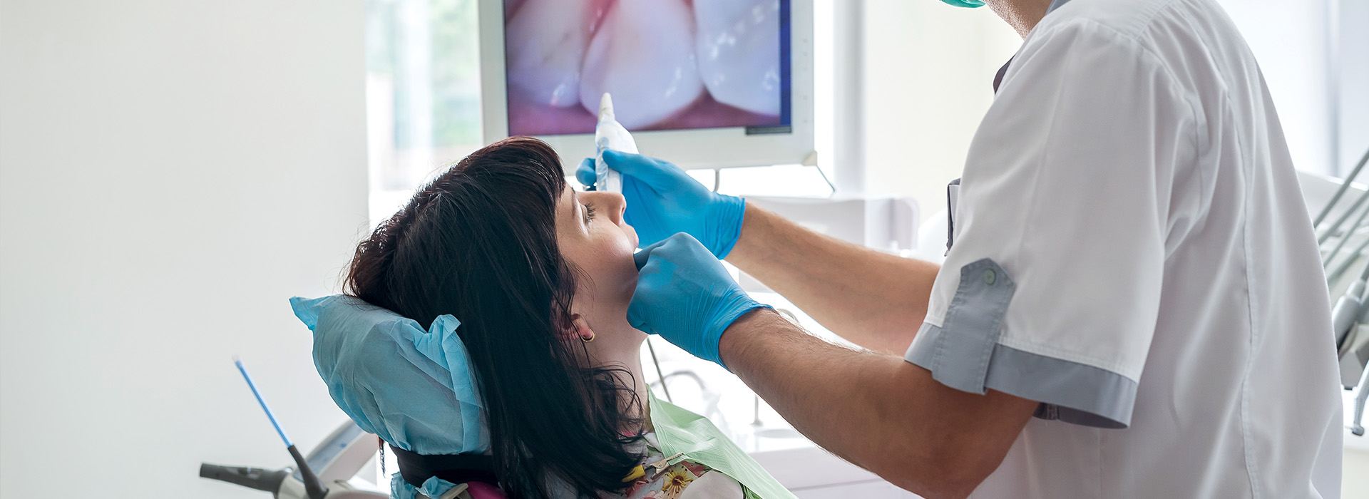 A dental hygienist performing oral care on a patient using a mirror.