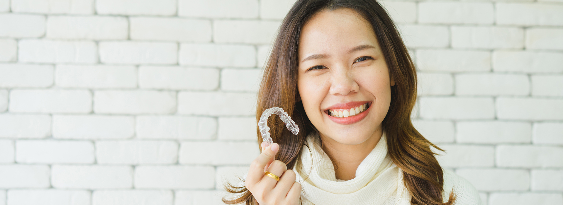 A woman holding up a toothbrush with a smile on her face.