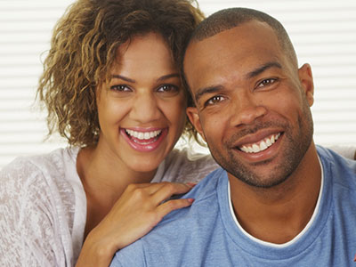 A man and woman smiling at each other against a white background.