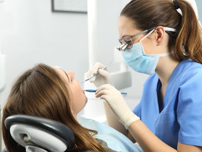 A dental hygienist performing a cleaning procedure on a patient s teeth.