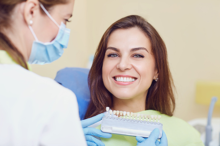 A woman with a broad smile receiving dental care from a professional in a dental office setting.