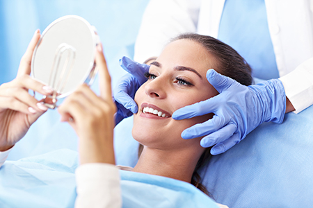The photo shows a woman lying on an examination table with her face partially obscured by a magnifying mirror held by a medical professional, who appears to be conducting a skin analysis or examination.