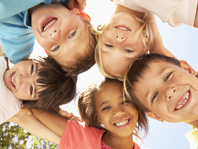 The image shows a group of children posing together with smiles on their faces, looking at the camera.