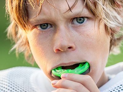 The image shows two photos of a young person with blonde hair, holding a green object close to their mouth, possibly a toothbrush, with one photo depicting a close-up view of the object.